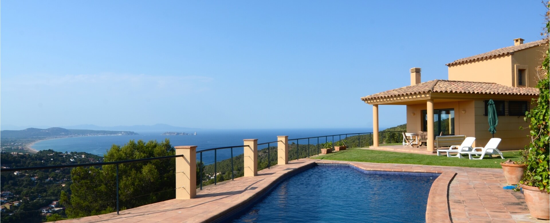 Sala d'estar lluminosa d'un habitatge amb grans finestrals i vistes a la Costa Brava